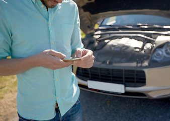 Image showing close up of man with smartphone and broken car