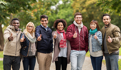 Image showing happy friends showing thumbs up at autumn park