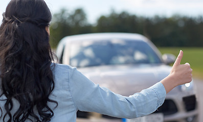 Image showing woman hitchhiking and stopping car with thumbs up