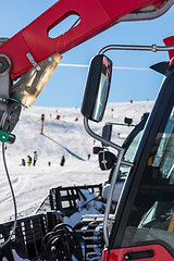 Image showing Skiers and snow-grooming machine