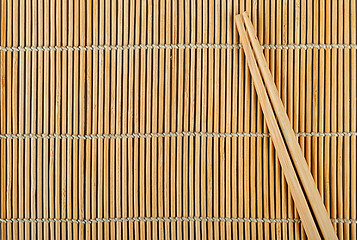 Image showing Bamboo sushi mat and chopsticks on top