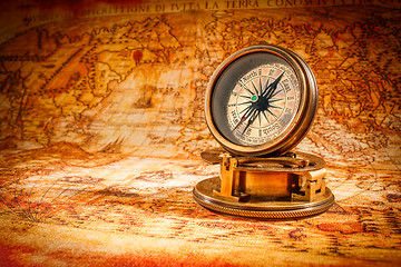 Image showing Vintage compass lies on an ancient world map.