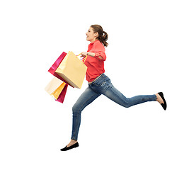 Image showing smiling young woman with shopping bags jumping