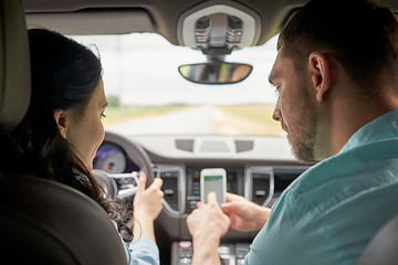 Image showing happy man and woman with smartphone driving in car