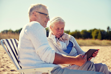 Image showing happy senior couple with tablet pc on summer beach