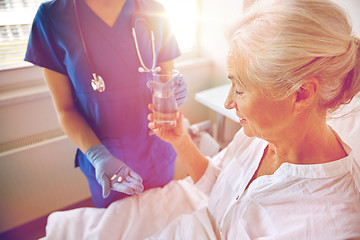 Image showing nurse giving medicine to senior woman at hospital