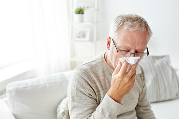 Image showing sick senior man with paper wipe blowing his nose