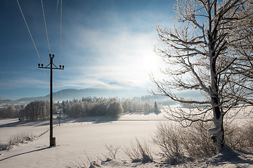 Image showing Austrian Winter Wonderland with mountains, a power pole in fresh snow and haze