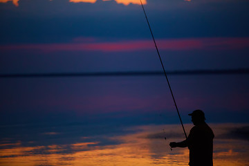 Image showing Silhouette of fishermen on quiet ocean with rays sunset