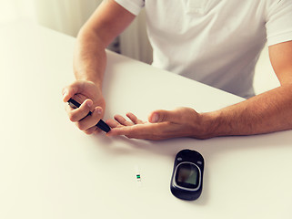 Image showing close up of man checking blood sugar by glucometer