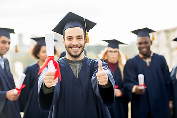 Image showing happy students with diplomas showing thumbs up