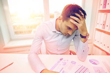 Image showing stressed businessman with papers in office