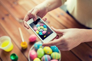 Image showing close up of hands with easter eggs and smartphone