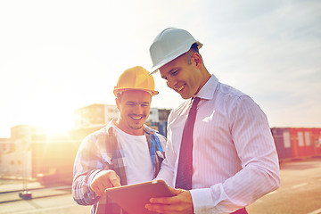 Image showing happy builders in hardhats with tablet pc outdoors