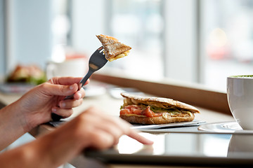 Image showing woman with tablet pc and panini sandwich at cafe