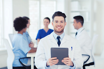 Image showing happy doctor with tablet pc over team at clinic