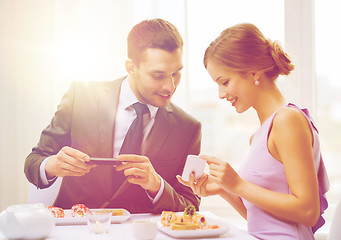 Image showing smiling couple with sushi and smartphones