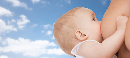 Image showing close up of breastfeeding baby over blue sky