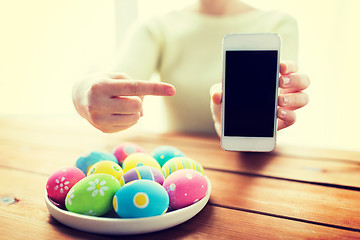 Image showing close up of hands with easter eggs and smartphone