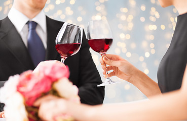 Image showing close up of couple clinking red wine glasses