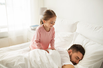 Image showing little girl waking her sleeping father up in bed