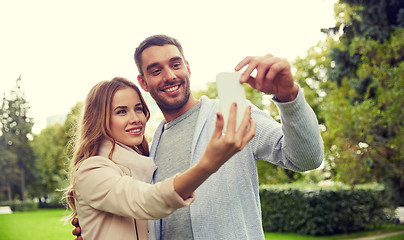 Image showing happy couple with smartphone taking selfie in park