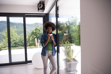 Image showing African American woman drinking coffee looking out the window