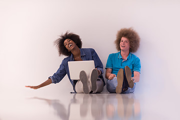 Image showing multiethnic couple sitting on the floor with a laptop and tablet