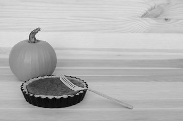 Image showing Fork with a small pumpkin pie on wood