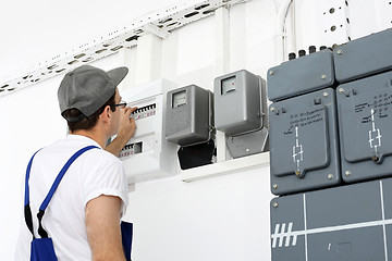 Image showing Electrician repairs dashboard. Electrical repair, switching current. An electrician checks the status of the counter.