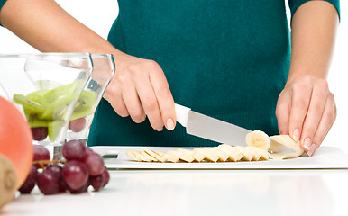 Image showing Cook is chopping banana for fruit dessert