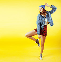 Image showing young pretty teenage girl emotional posing on yellow background, fashion lifestyle people concept 