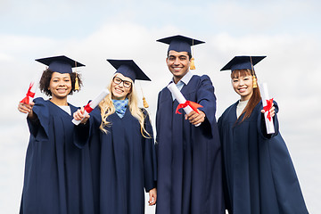 Image showing happy students in mortar boards with diplomas