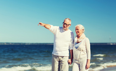 Image showing happy senior couple walking on summer beach