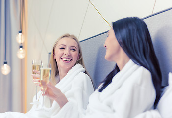 Image showing smiling girlfriends with champagne glasses in bed