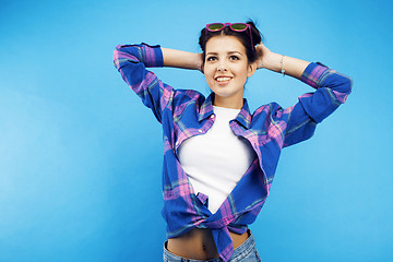 Image showing young pretty teenage hipster girl posing emotional happy smiling on blue background, lifestyle people concept close up