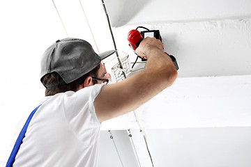 Image showing Electrician repairs installations holding screwdriver and gauge.