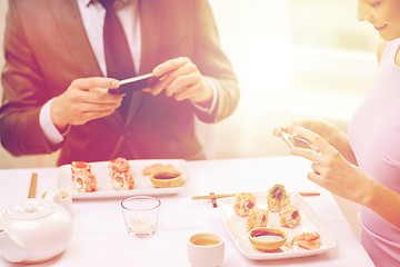 Image showing close up of couple with smartphones at restaurant