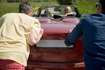 Image showing happy friends pushing broken cabriolet car