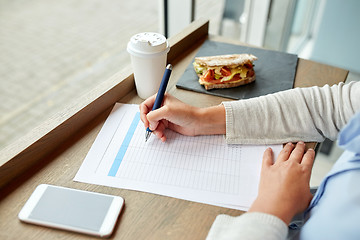 Image showing woman with paper form having lunch at cafe