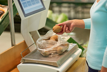 Image showing woman weighing potatoes on scale at grocery store