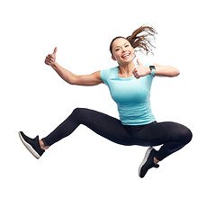 Image showing happy smiling sporty young woman jumping in air