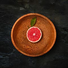 Image showing Grapefruit citrus fruit halves on wooden plate