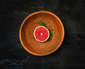 Image showing Grapefruit citrus fruit halves on wooden plate