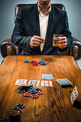 Image showing The man, chips for gamblings, drink and playing cards