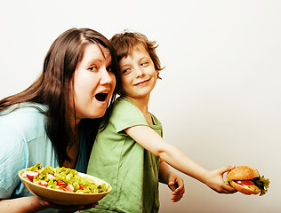 Image showing fat woman holding salad and little cute boy with hamburger on white background