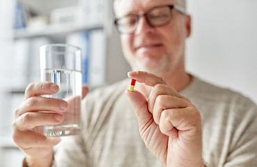 Image showing close up of old man hands with pill and water