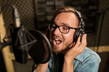 Image showing man with headphones singing at recording studio