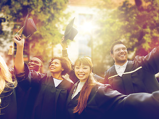 Image showing happy students or bachelors waving mortar boards