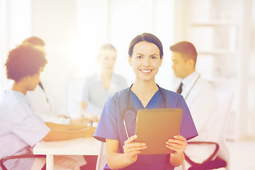 Image showing happy doctor with tablet pc over team at clinic